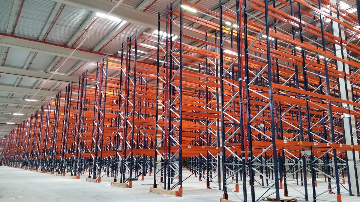 Empty orange and blue pallet racks lined up in a large warehouse